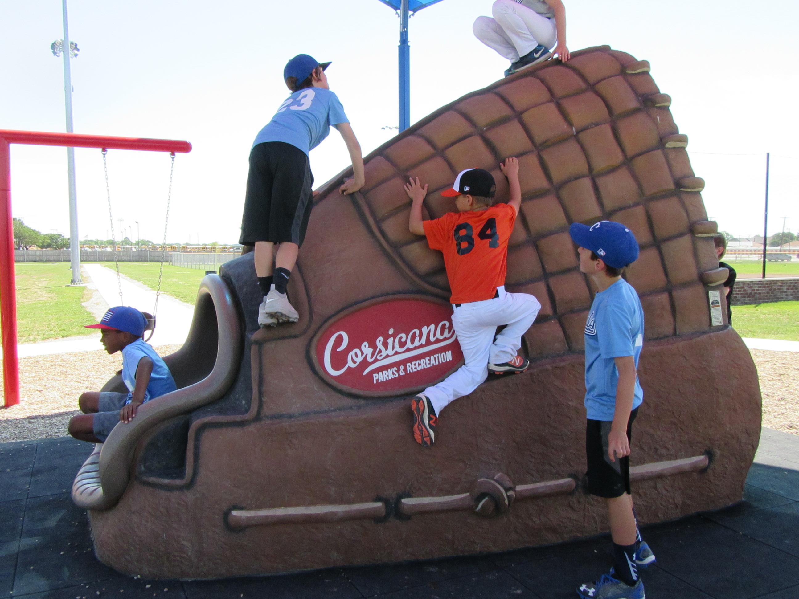 Kids climbing on large baseball glove statue
