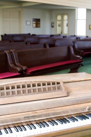 Piano with Pews in the Background